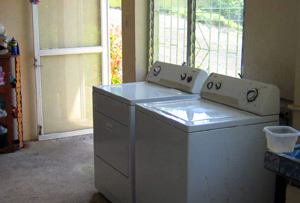 A large laundry room has modern appliances and plenty of spacing for shelving and hanging bedding.